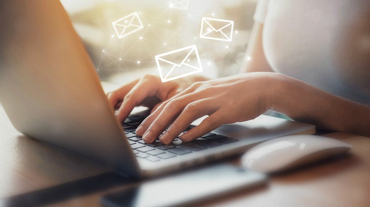 woman typing on laptop with email symbols